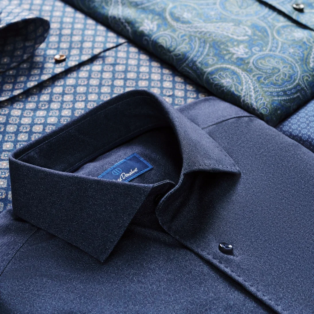 A navy button-down collar folded over a patterned pocket square