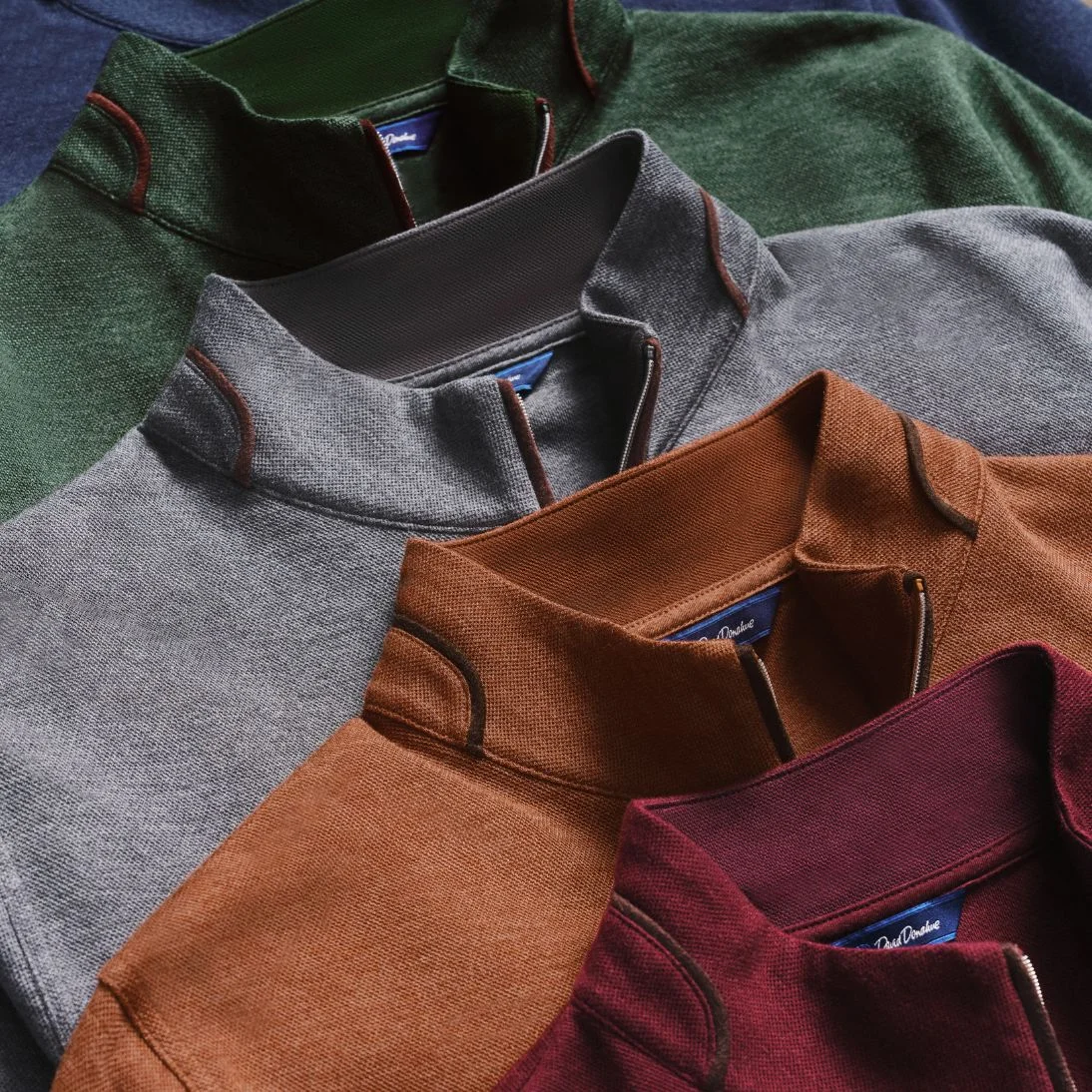 Quarter-zip sweaters in green, grey, rust and burgundy layered together