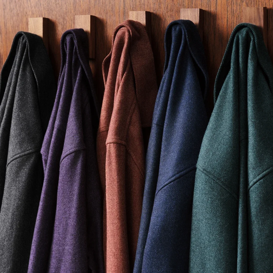 A row of wool jackets hanging from wooden pegs